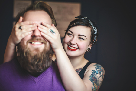 young couple in love with tattoos having fun, the girl closes hands eyes guyの写真素材