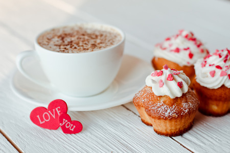 Beautiful coffee Cup with heart cupcake on white wooden backgroundの写真素材