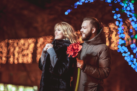 loving young couple walking outdoors in winter. Girl holding a flowerの写真素材