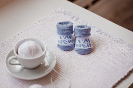baby socks and ball of yarn in white coffee Cup on the tableの写真素材