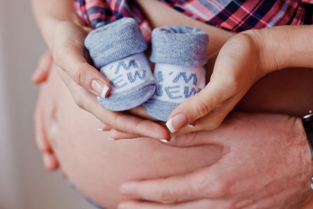 Small shoes for the unborn baby in the belly of pregnant womanの写真素材