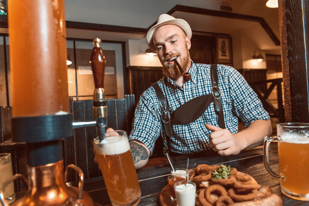 Happy smiling man with leather trousers (lederhose) tasting fresh brewed beer.の写真素材