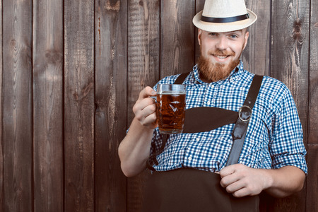 Happy smiling man with leather trousers (lederhose) tasting fresh brewed beer.の写真素材