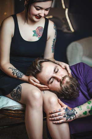 young couple in love with tattoos, the guy is lying on the lap of the girlの写真素材