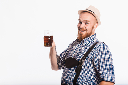 Happy smiling man with leather trousers (lederhose) holds oktoberfest beer glass. Isolated on white backgroundの写真素材