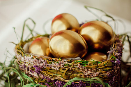 Golden easter eggs in nest on white wooden backgroundの写真素材