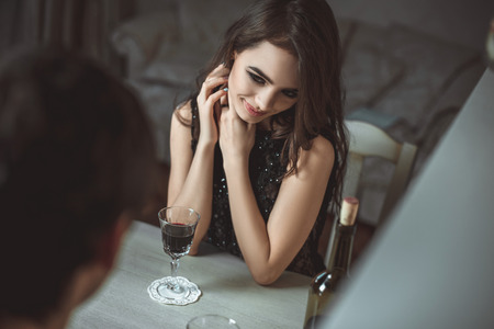 Beautiful young couple with glasses of red wine in luxury restaurantの写真素材