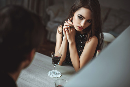 Beautiful young couple with glasses of red wine in luxury restaurantの写真素材