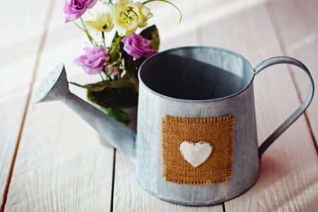 a beautiful old watering can and a bouquet of flowers on white boardsの写真素材