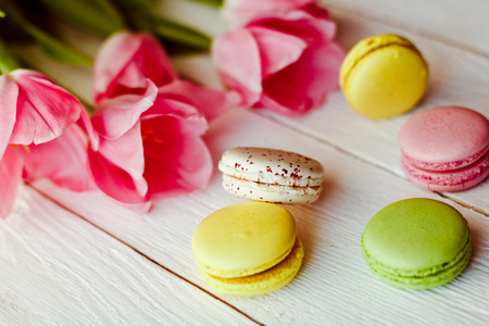 A beautiful bouquet of pink tulips with colorful macaroons on white wooden backgroundの写真素材