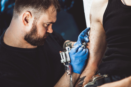 master tattoo artist with a beard makes gloves tattoo on hand menの写真素材