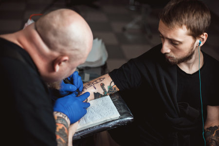 master tattoo artist with a beard makes gloves tattoo on hand menの写真素材