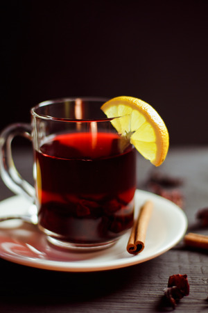 A Cup of hibiscus tea from Sudanese rose with lemon and cinnamon sticks on a black wooden backgroundの写真素材