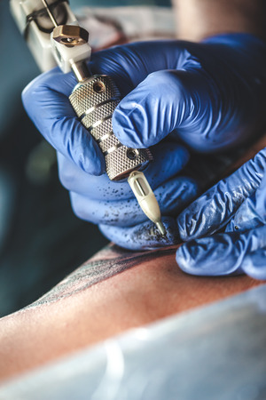 master tattooist does the tattoo in gloves on the hand of the manの写真素材