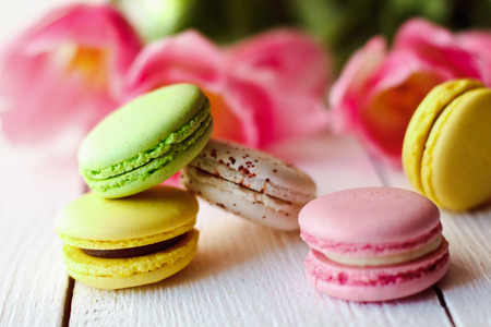 A beautiful bouquet of pink tulips with colorful macaroons on white wooden backgroundの写真素材