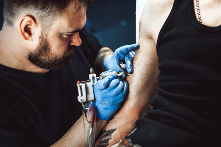 master tattoo artist with a beard makes gloves tattoo on hand menの写真素材