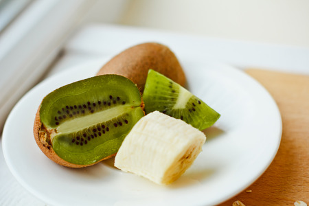 Banana and kiwi sliced on a white plate. Fruits for a healthy dietの写真素材