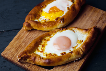 Hachapuri on Adjara. Beautiful open pies khachapuri with egg and onions on wooden backgroundの写真素材