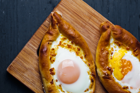 Beautiful open pies khachapuri with egg and onions on wooden backgroundの写真素材