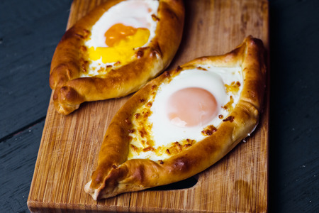 Beautiful open pies khachapuri with egg and onions on wooden backgroundの写真素材