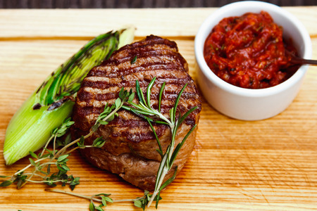 Beautiful juicy well done steak with sauce on a wooden Boardの写真素材