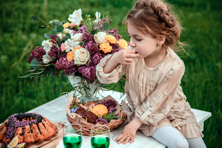 Little baby girl eats chocolate cake in nature at a picnic.の写真素材
