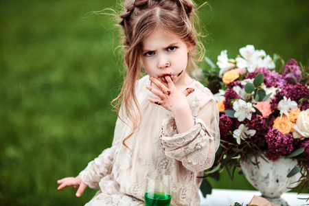 Little baby girl eats chocolate cake in nature at a picnic.の写真素材