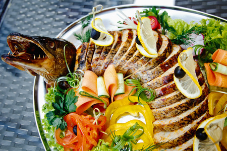 Stuffed pike decorated with vegetables and fruits with the greens. Very beautiful restaurant dishの写真素材