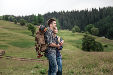 A couple hikers Hiking with backpacks walk along a beautiful mountain area.