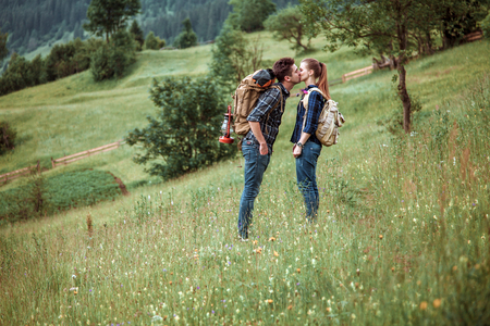 Couple of hikers Hiking with backpacks walk along a beautiful mountain area, are kissing.の写真素材