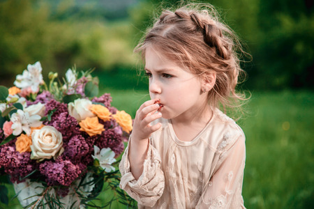 Little baby girl eats chocolate cake in nature at a picnic.の写真素材