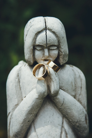 stylish pair of golden wedding ring on the old statues woman, time conceptの写真素材