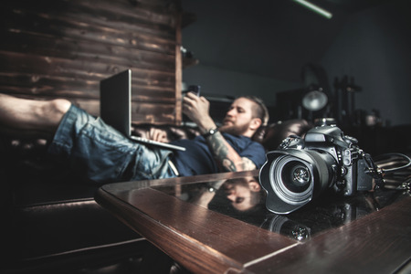 Male boss lying on the sofa in his office, working on laptop and looking at cell phone. The concept of the creative process, skill and favorite pastimeの写真素材