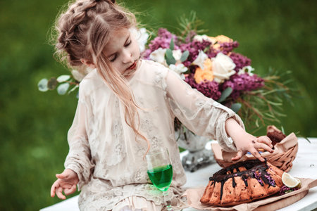 Little baby girl eats chocolate cake in nature at a picnic. The concept of a happy childhoodの写真素材