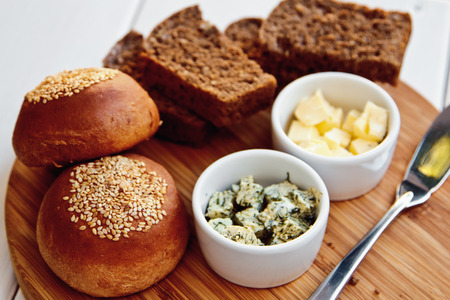 Green and butter with French baguette and black bread on a wooden Boardの写真素材