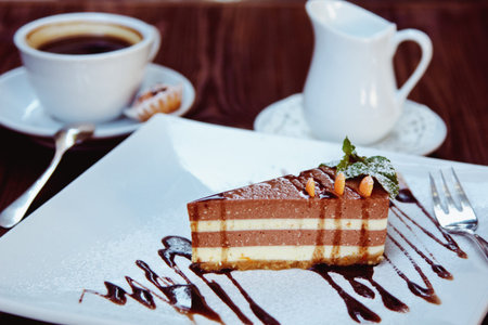 Cheesecake slice with melted chocolate on white plate and coffee