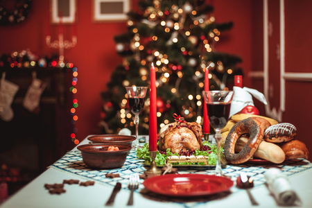 Christmas dinner by candlelight, table setting. Thanksgiving table with baked turkey in a decorated room with a Christmas tree.の写真素材