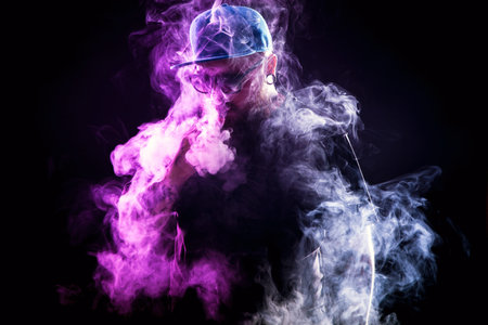 Men with beard  in sunglasses vaping and releases a cloud of vapor.