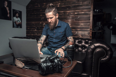Male boss sitting on the couch in his office, working on laptop