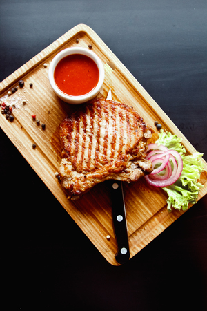 Beautiful juicy pork steak cooked on the grill with caramelized onionsの写真素材