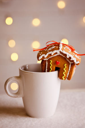 Gingerbread house put on a white Cup on the background of Golden bokehの写真素材