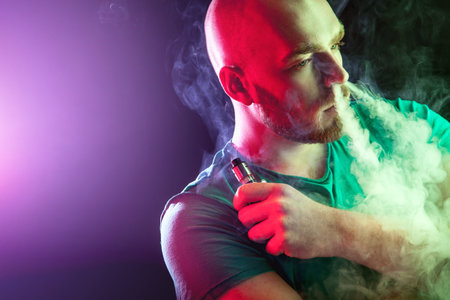 Men with beard  in sunglasses vaping and releases a cloud of vapor.Men with beard  in sunglasses...