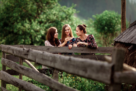 Beautiful girls in long dresses walk in nature near the wooden fence. The concept of travel and leisureの写真素材