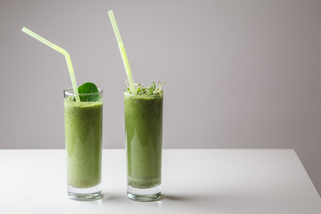 Freshly blended green fruit smoothie in glass with straw. Theme of raw food, live food, healthy eating backgroundの写真素材