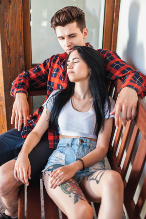 The guy fondly looks at his sleeping girlfriend, sitting on the bench. Beautiful young couple. The concept of the care, love, devotion and loyaltyの写真素材