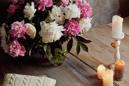 Beautiful romantic interior in loft style with candles and a bouquet of peoniesの写真素材