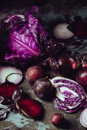Beautiful dark background with fruits and vegetables of one color: blue cabbage, beets, onions, Basil, plumの写真素材