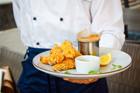 Fish and chips on a white plate in the hands of the chefs at the restaurantの写真素材