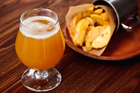Potato chips and glass of beer on a wooden table.の写真素材