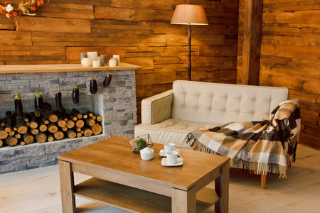Home comfort. Armchair near the fireplace with firewood. Photo of interior of room with a wooden wall, wreath and garlands, Christmas atmosphereの写真素材